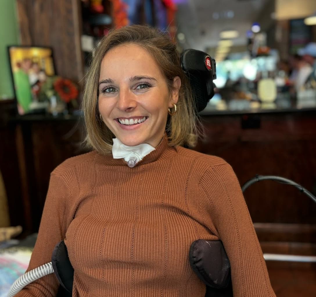 Rebecca Koltun smiling, close-up portrait in a rust-brown sweater.