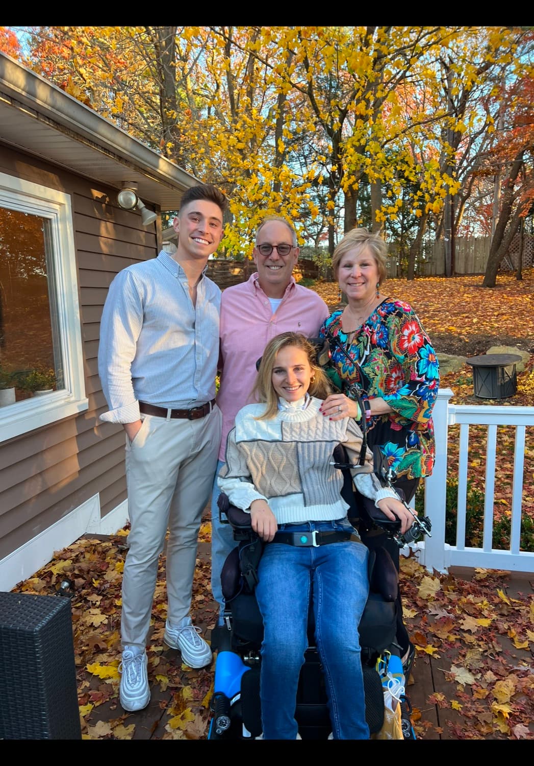 Rebecca with her family outdoors in autumn, in her wheelchair.