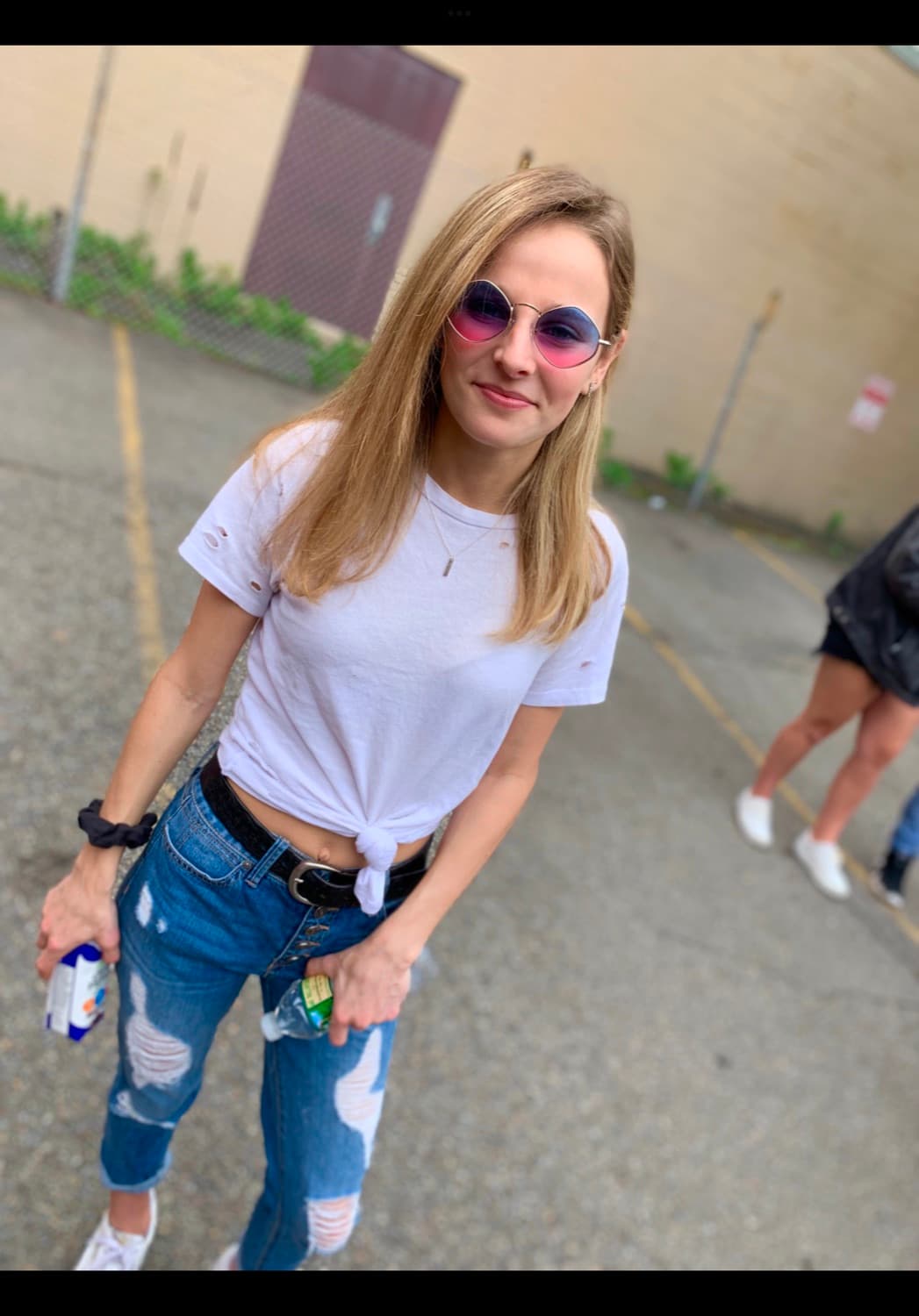 Rebecca standing outdoors in a white tee and jeans before her injury.